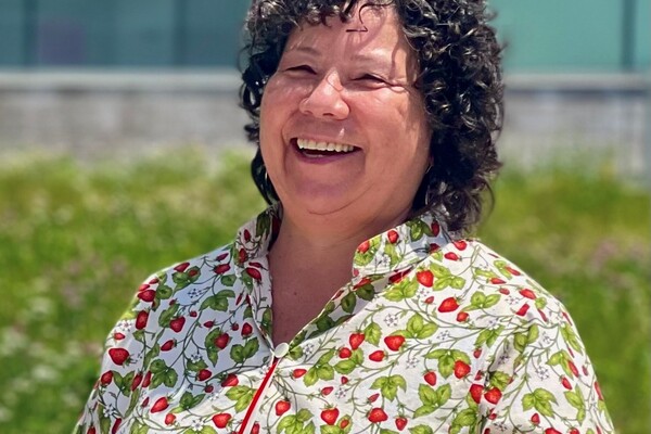 An outdoor portrait of Cindy White smiling, wearing a patterned shirt and looking to the left